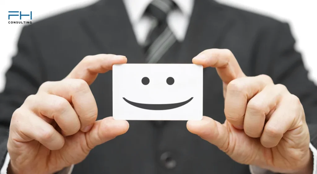 Ein Mann im Anzug hält eine Visitenkarte mit einem lächelnden Smiley – Symbol für digitale Kundennähe. Digitale Visitenkarte oder Papiervisitenkarte?