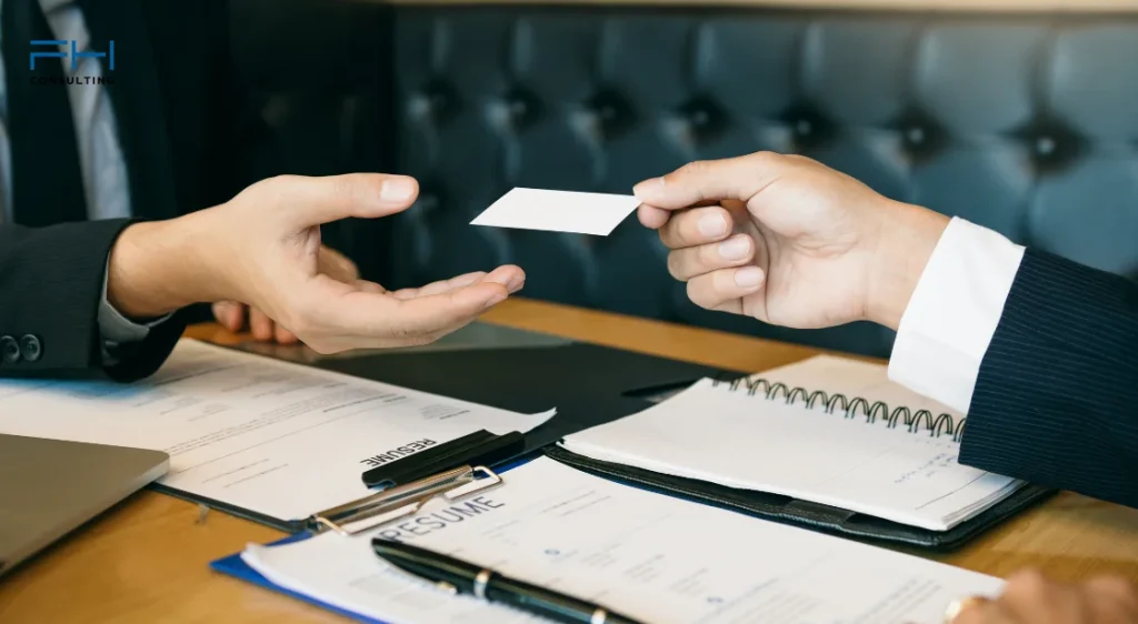 Zwei Geschäftspersonen tauschen analoge Visitenkarten in einem Business-Meeting aus.